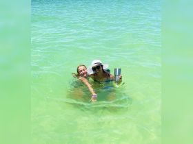 Two friends enjoy a refreshing swim in crystal-clear waters, capturing the essence of summer fun and beach adventures.