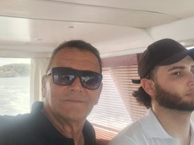 Two men pose for a selfie inside a boat, showcasing a relaxed atmosphere while enjoying their time on the water.