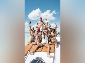 A lively group celebrates on a boat, enjoying drinks and a birthday cake under the sun — perfect for unforgettable party experiences on the water.