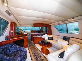 A stylish interior view of a yacht's cabin featuring comfortable seating and a well-equipped bar area, perfect for relaxing while cruising on the water.