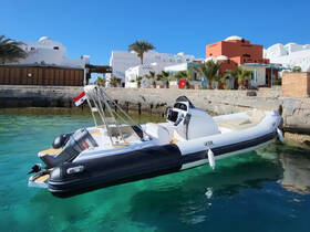 A sleek speedboat docked in clear turquoise waters, showcasing its modern design against a picturesque backdrop of coastal architecture.