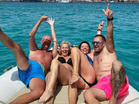 A lively group of friends enjoys a fun day on the water, celebrating and soaking up the sun on a boat. Perfect for unforgettable summer memories!