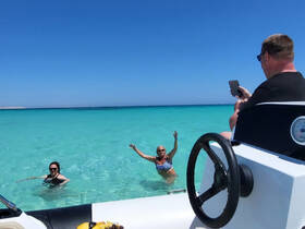 A lively scene of friends enjoying a refreshing swim in crystal-clear turquoise waters, capturing the essence of a perfect day on the water.