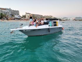 A lively group enjoys a day on the boat 'My Dream' near the beach, capturing the essence of fun and celebration on the water.
