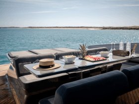 A beautifully arranged table on a yacht featuring fresh fruits, snacks, and drinks, perfect for enjoying a luxurious day on the water.