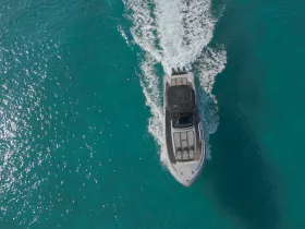 Aerial view of a sleek speedboat cruising through crystal-clear turquoise waters, showcasing the beauty of boating adventures.
