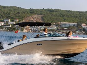 A group enjoys a thrilling ride on a speedboat, showcasing the excitement of on-water adventures against a scenic backdrop.