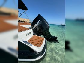 A close-up view of a Bowfin boat featuring a Suzuki outboard motor, anchored in clear turquoise waters — perfect for exploring coastal destinations.