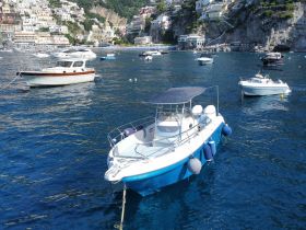 A picturesque view of a speedboat anchored in clear blue waters, surrounded by a scenic coastal backdrop — perfect for exploring the Amalfi Coast.