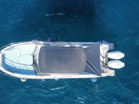 Aerial view of a sleek boat cruising through crystal-clear waters, showcasing its elegant design and spacious deck.