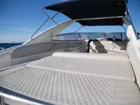 A spacious lounge area inside a boat, featuring comfortable seating and a sleek design, perfect for relaxing while enjoying the open water.
