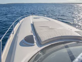 A sleek view of the front deck of a yacht, showcasing its elegant design against the shimmering blue waters — perfect for luxury boating experiences.