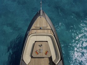 Aerial view of a luxurious lounge area on a boat, featuring comfortable seating and a stylish table, perfect for relaxing on the water.