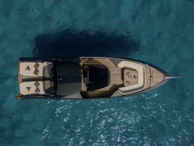 A stunning aerial view of a sleek yacht cruising through crystal-clear waters, showcasing its elegant design and luxurious seating areas.
