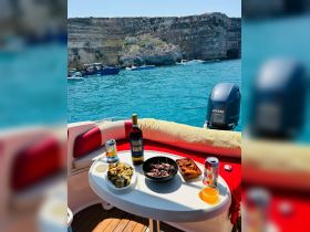 A beautifully arranged table featuring delicious food and drinks on a boat, perfect for enjoying a relaxing day on the water with friends or family.