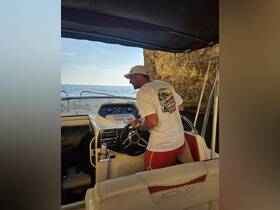 A man navigates the helm of a boat, showcasing the interior setup and controls, perfect for those interested in boating experiences.