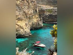 A vibrant scene of a boat in crystal-clear waters surrounded by stunning cliffs, perfect for a day of exploration and adventure.