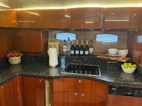 A well-appointed boat kitchen featuring elegant cabinetry, a sleek countertop, and a selection of beverages, perfect for entertaining guests on board.