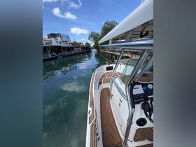 A sleek center console boat is docked in calm waters, showcasing its stylish design and the serene surroundings of the waterfront.