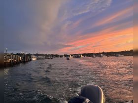 A stunning sunset over the harbor, showcasing boats and the tranquil waters — perfect for evening cruises and scenic views.