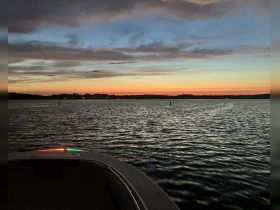 A serene sunset view from the bow of a boat, showcasing tranquil waters and a colorful sky — perfect for evening cruises.