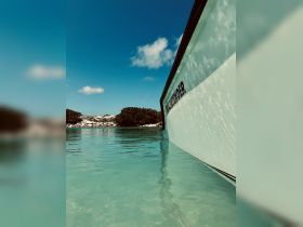 A close-up view of a boat's side, showcasing its sleek design against a backdrop of clear turquoise waters and a blue sky, perfect for showcasing marine adventures.