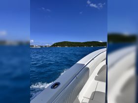 A scenic view from the deck of a boat cruising through vibrant blue waters, showcasing the lush green island in the background — perfect for exploring coastal destinations.