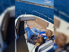 A couple relaxes on the deck of a boat, enjoying a sunny day on the water — perfect for unwinding and taking in the beautiful scenery.