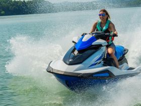 A woman joyfully rides a jet ski, creating splashes in the water — a thrilling moment showcasing the excitement of water sports.
