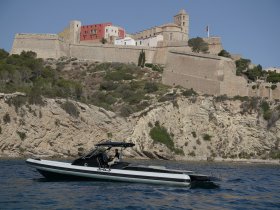 A sleek speedboat navigates the waters near a historic fortress, showcasing the perfect blend of adventure and scenic beauty.