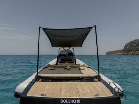 A sleek view of the 'Bolero III' boat showcasing its spacious deck and shade, perfect for relaxing on the water.