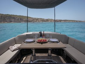A beautifully arranged dining area on a boat featuring fresh fruit and wine, perfect for enjoying meals while cruising in turquoise waters.