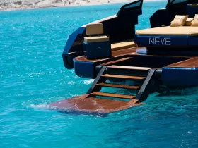 A stunning close-up of the back of a luxury yacht named 'NEVE', showcasing its sleek design and steps leading into the vibrant turquoise waters, perfect for a day of relaxation and adventure.