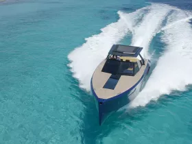 An aerial view of a sleek speedboat cruising through crystal-clear turquoise waters, showcasing its elegant design and performance on the open sea.