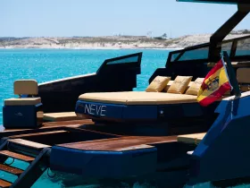 A stunning view of the yacht 'NEVE' showcasing its sleek design and luxurious seating, set against a backdrop of crystal-clear turquoise waters.
