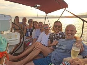 A joyful group celebrates at sunset aboard a boat, enjoying drinks and each other's company — perfect for memorable gatherings on the water.