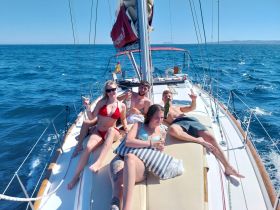 A lively group enjoys a sunny day sailing, celebrating with drinks on the deck of a yacht — perfect for summer adventures on the water.