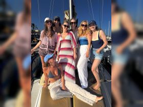 A joyful group of friends poses together on the deck of a yacht, capturing the essence of friendship and celebration on the water.