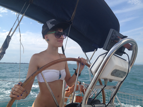 A young woman confidently steers a sailboat, showcasing the thrill of sailing on open waters — perfect for adventure seekers.