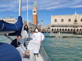 A lively group enjoys a sailing experience in Venice, showcasing the stunning architecture of the city as a backdrop — perfect for memorable moments on the water.