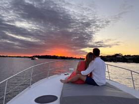 A couple enjoys a romantic sunset on the deck of a yacht, creating the perfect backdrop for special moments and celebrations on the water.
