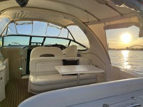 A cozy interior view of a boat's cabin featuring comfortable seating and a table, perfect for relaxing while enjoying scenic waterfront views.
