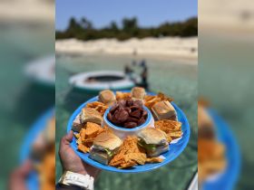 A vibrant platter of snacks featuring sandwiches and chips, perfect for enjoying on a boat trip or beach day.