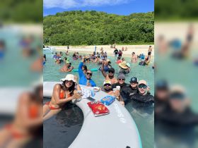 A lively group enjoys a beach party, relaxing in the water with drinks and snacks, creating unforgettable memories in a tropical paradise.