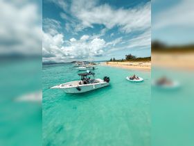 A lively scene at a beautiful beach with a group enjoying time on a boat and floating in the water — perfect for sandbar stops and family fun in the sun.