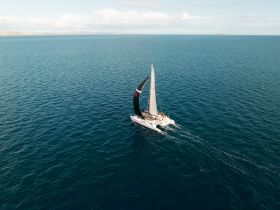 A stunning aerial view of a catamaran sailing through clear blue waters, showcasing the beauty of maritime adventures.