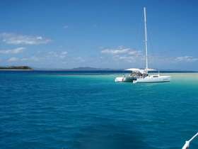 A stunning catamaran sails through crystal-clear turquoise waters, showcasing the beauty of a tropical paradise.