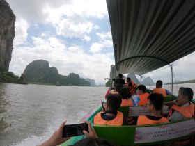 A lively group enjoys a scenic boat tour, taking in the stunning limestone formations and lush landscapes — a perfect adventure in nature.