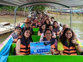 A lively group aboard a boat, celebrating with life jackets and a welcome sign for a trip to Phuket — perfect for group adventures and memorable experiences on the water.