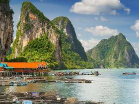 Breathtaking view of towering limestone cliffs and traditional boats in a serene bay, showcasing the stunning natural beauty of the coastline.